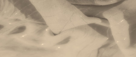 Blurred close-up of beige fabric with shimmering stripes, gently folded to showcase its texture and...