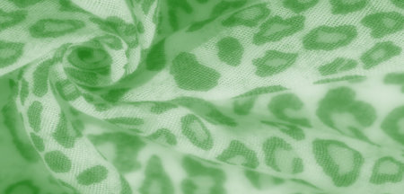 Blurred soft green fabric close-up with an abstract leopard-like pattern. The flowing folds add a...