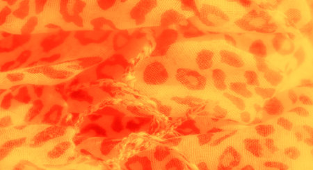 Blur of yellow fabric featuring a red-orange leopard print with a mesh texture. The abstract...