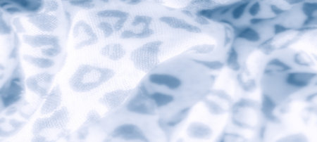 Blur effect captures the flowing texture of blue and white fabric with an abstract, leopard-inspired pattern. The soft folds add a touch of elegance and depth, perfect for design inspiration.の写真素材