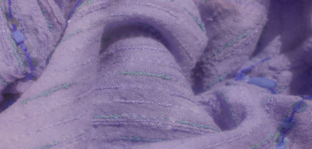 Blur of a lavender fabric with green and blue stitched patterns, detailed with shiny sequins in a line, adding texture and a gentle glow to the fabric's surface.の写真素材