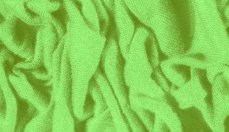 Blur of vibrant green fabric with a crumpled and textured appearance, displaying depth and character. The intricate folds emphasize the fabric's dynamic flow and movementの写真素材