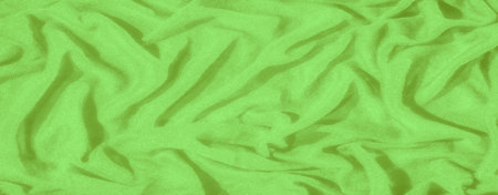Blur of soft green fabric with a textured, crumpled surface. The bright green color and intricate...