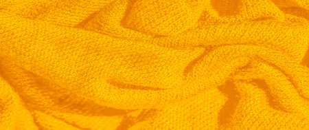 Blur of bright yellow fabric in soft folds, showing a cozy, inviting texture, ideal for textile...