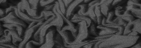 Blurred details of textured fabric, displaying a moody interplay of light and shadow across the...
