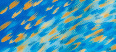 Blur of blue fabric featuring vibrant orange patterns, creating a lively, abstract aesthetic. The...
