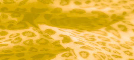 Blur of warm yellow fabric with subtle leopard-like patterns, exuding a gentle, organic texture through its intricate folds and flowing design.の写真素材