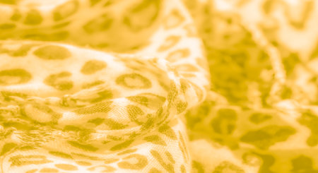 Blur of yellow fabric with abstract, soft patterns resembling animal print. The fabric's delicate texture adds a sense of sophistication and subtle dimension.の写真素材