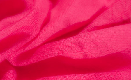 Blur. The vivid pink fabric's texture and soft folds evoke a sense of elegance and warmth. This luxurious material captures light beautifully, highlighting the smoothness and depth of each contour.の写真素材
