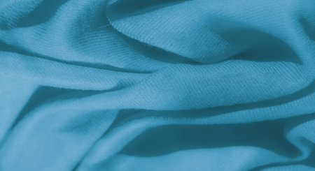 Blur of blue fabric in a soft, smooth texture, elegantly folded in delicate waves. This abstract...
