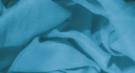 Blur of blue fabric intricately folded with gentle waves and soft texture. The delicate pattern creates a calm, abstract background, highlighting the fabric's softness and elegance.の写真素材