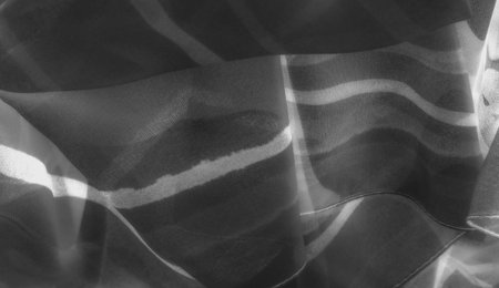 Blur of curved fabric shadows and highlights, creating an abstract grayscale image. Smooth textures emphasize the play of light, with tonal depth and softnessの写真素材