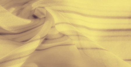 Blur of flowing yellow fabric with overlapping shadows and folds, creating a soft, dynamic composition. The warm tones and textures lend a sense of elegance and depth.の写真素材