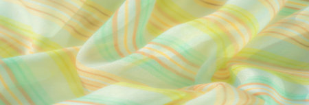 Blur of flowing pastel fabric with green and yellow stripes, capturing a soft, smooth texture that...