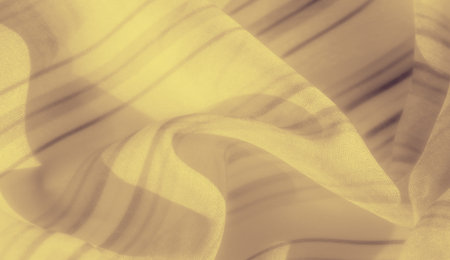 Blur captures a yellow fabric adorned with gentle stripes, folding gracefully to exhibit a refined and soft texture that complements its warm, inviting color.の写真素材