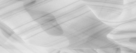 Blurred gentle waves and folds in white fabric, featuring faint striping and subtle shadows, convey a sense of calm and refined beauty in a minimalist style.の写真素材