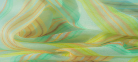 Blur effect on smooth fabric with soft green, yellow, and orange stripes. The fabric's light, airy...