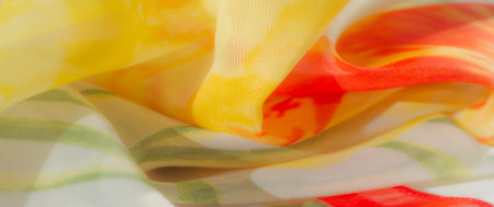 Blur. This close-up highlights a flowing fabric with a mix of vibrant orange and yellow florals,...