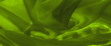Blurred neon green fabric with folds and gentle curves, highlighted by the translucent mesh and subtle floral shapes in the background, giving a delicate, ethereal feel.の写真素材