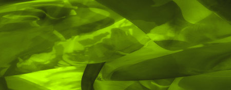Blur, close-up of green fabric with swirling folds and intricate textures. The light and shadow play enhances the abstract, dreamy quality of the image.の写真素材
