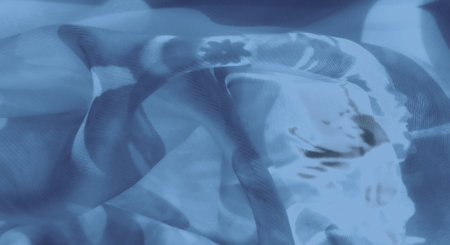 Blur of blue fabric gracefully layered, creating an interplay of shadow and light. The sheer texture enhances the fabric's gentle folds and calming ambiance.の写真素材