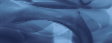Blurred layers of blue fabric overlap in abstract waves, creating a textured visual with calming shades and soft curves that suggest movement and flow in a serene textile design.の写真素材