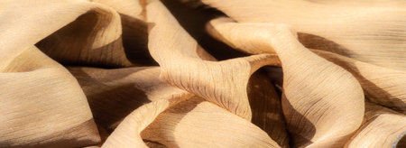 Blur - Soft, light brown fabric folds arranged in wavy, abstract patterns. The delicate texture highlights its quality, casting soft shadows and warm, inviting tones.の写真素材