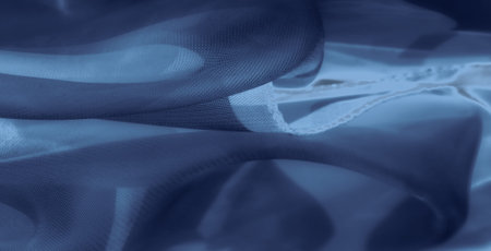 Blur of a refined blue textile with a flowing mesh pattern, creating an elegant and peaceful atmosphere. Soft light enhances the smooth, wavy folds and delicate fabric details.の写真素材