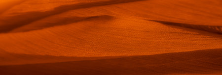 Blurred orange fabric with soft shadows and a rich texture, creating a warm and inviting feel. Ideal for projects emphasizing softness, depth, and elegant fabric design.の写真素材