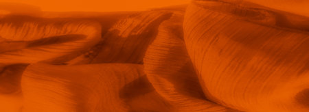 Blur Close-up of orange fabric with delicate folds and subtle shadows, creating a dynamic and inviting texture. The glowing hue and wavy details offer a cozy, warm feel.の写真素材