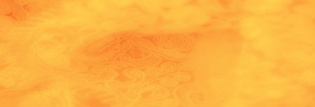 Blurred vibrant yellow fabric with detailed spirals and floral motifs, creating a warm and soft texture that accentuates the intricate design with a lively appearance.の写真素材