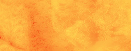 Blur of a yellow fabric with swirling, intricate designs that bring depth to the visual. The plush texture and inviting hue create a refined look suitable for modern decorの写真素材