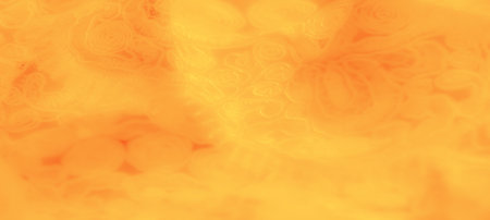 Blurred abstract yellow fabric with delicate, spiraling textures that appear like intricate carvings, adding a warm glow and a sense of motion across the surface.の写真素材