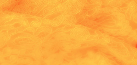 Blur. A close-up of a richly textured yellow fabric with swirling and abstract floral designs, capturing the glowing patterns illuminated by soft lighting that enhances its artistic appeal.の写真素材
