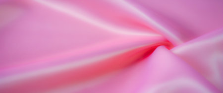 Blurred close-up of pastel pink satin fabric with intricate folds radiating a smooth, glossy finish The elegant flow and shine capture the essence of luxury and sophistication ideal for textile designの写真素材