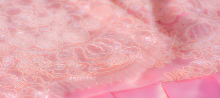 Blur, peach-colored lace fabric with intricate swirling patterns and floral details, emphasizing a delicate texture suitable for fashion, decor, or bridal designs.の写真素材