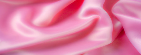 Blur, a close-up of soft pink satin fabric, folded and draped elegantly. The fabric's gentle flow and smooth texture add a refined and luxurious touch, ideal for a romantic aesthetic.の写真素材