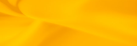 Blur of yellow fabric with elegant folds and shadows. The rich, warm yellow color and smooth texture create a dynamic, abstract background with gentle highlights and curves.の写真素材