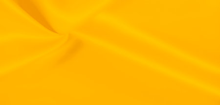 Blur. A bright yellow fabric with a luxurious, smooth texture and subtle folds. The vibrant color and soft appearance make it perfect for use in backgrounds or fabric-focused designs.の写真素材