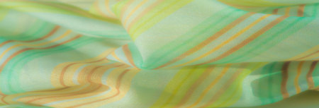 Blur effect on delicate fabric with green, yellow, and orange stripes. Gentle folds and a flowing...