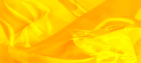 Blur of sunlit yellow fabric with smooth folds and luminous layers. The translucent fabric captures light beautifully, creating an energetic, fresh vibe perfect for artistic backgrounds.の写真素材