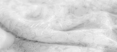 Blurred detailed shot of white lace fabric with floral embroidery and swirling patterns, creating an elegant and feminine design. The intricate weaving enhances the soft texture.の写真素材