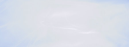 Blur of soft, light blue fabric with smooth, gentle folds, providing an airy, serene ambiance. Ideal as a subtle, calming background for designs and visuals.の写真素材