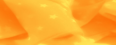 Blur of warm yellow fabric with star motifs, exuding a cozy and radiant feel. The gentle folds and glowing pattern create a serene background with an inviting warmth.の写真素材