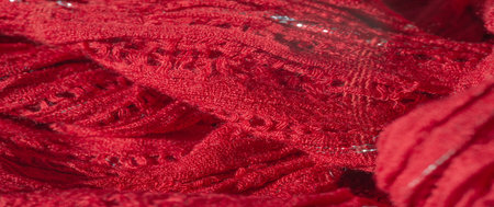 Blur of richly woven red fabric with layered texture and delicate silver accents, creating an...