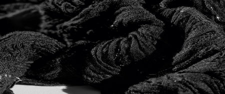 Blur in this close-up, the textured folds of black fabric weave together, creating depth and a luxurious visual, as light and shadow interplay over its intricate patterns.の写真素材