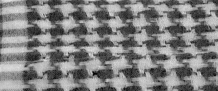 Blurred fabric in grayscale with a layered woven texture and intricate details. The close-up...