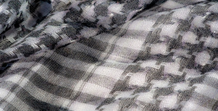 Blurred grayscale fabric with a refined woven pattern and soft folds. The texture and intricate...