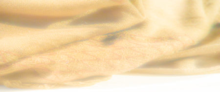 Blurred yellow fabric close-up with intricate woven details and a soft, cozy appearance. The warm, glowing texture enhances the inviting feel of this textile.の写真素材