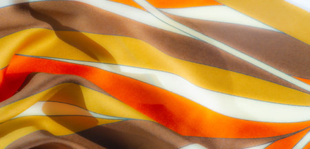 Blur effect on smooth, satin-like fabric with warm hues of orange, yellow, and brown, accented by...